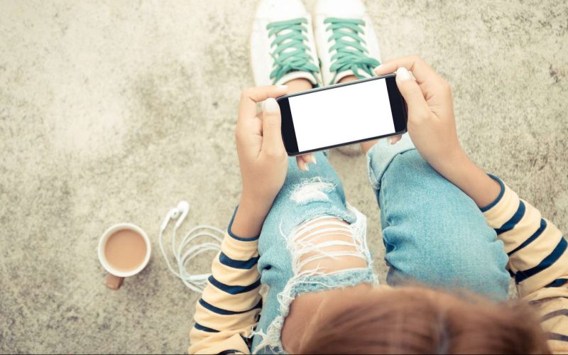 Pige sidder med sin telefon