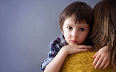 Mørkhåret dreng krammer mørkhåret kvinde i gul sweater