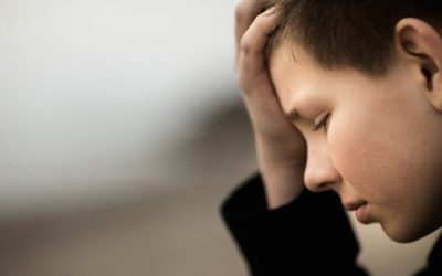Dreng set i profil holder hovedet med en hånd og kigger ned