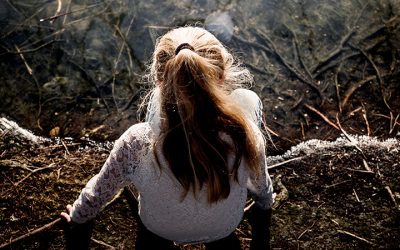 Pige set bagfra i fugleperspektiv sidder på jorden og kigger ned