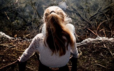 Pige set bagfra i fugleperspektiv sidder på jorden og kigger ned