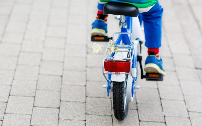 Barnecykel med en blomst bagpå der bliver cyklet