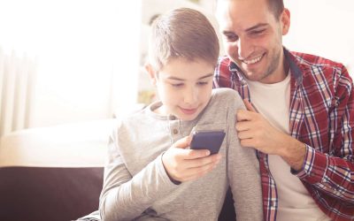 Far og barn sidder og kigger på en mobiltelefon