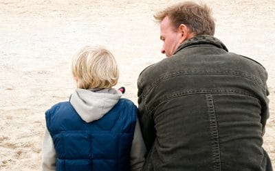 Far og søn sidder på en strand