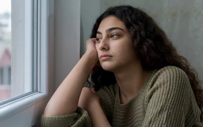 Mørkhåret pige kigger ud af et vindue