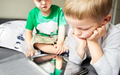 To små, lyshårede drenge kigger ned på en iPad.