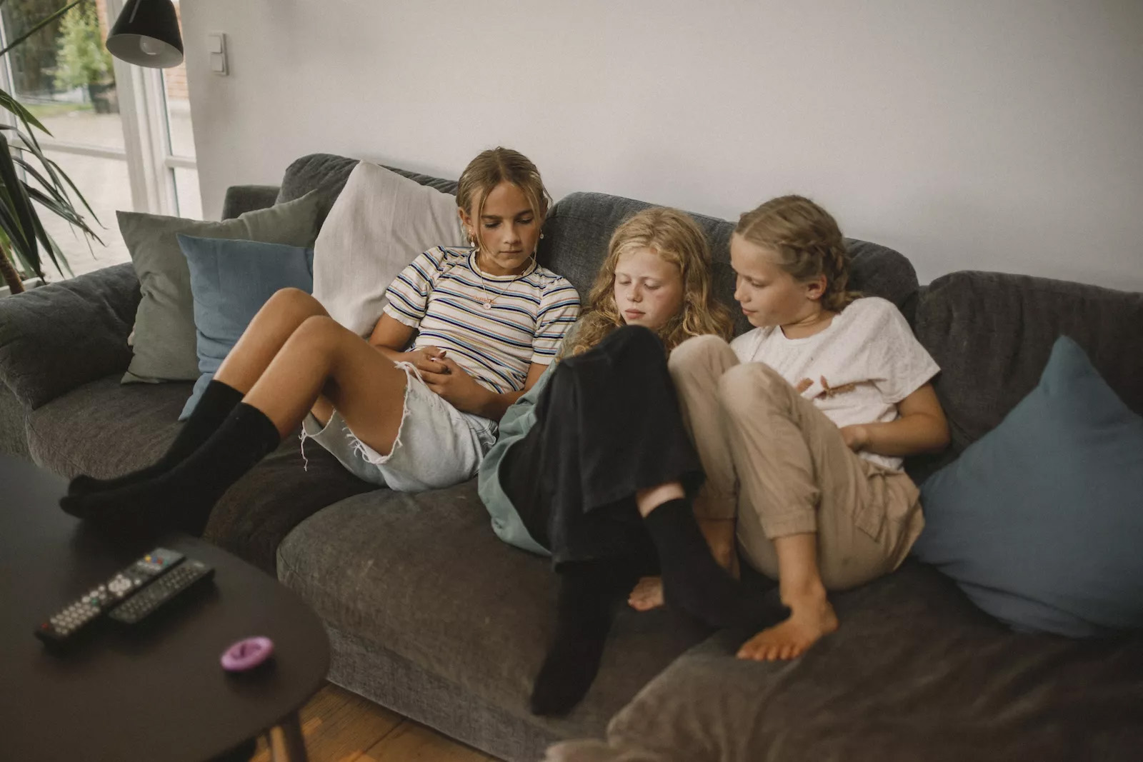 Tre piger på en sofa kigger på en telefon