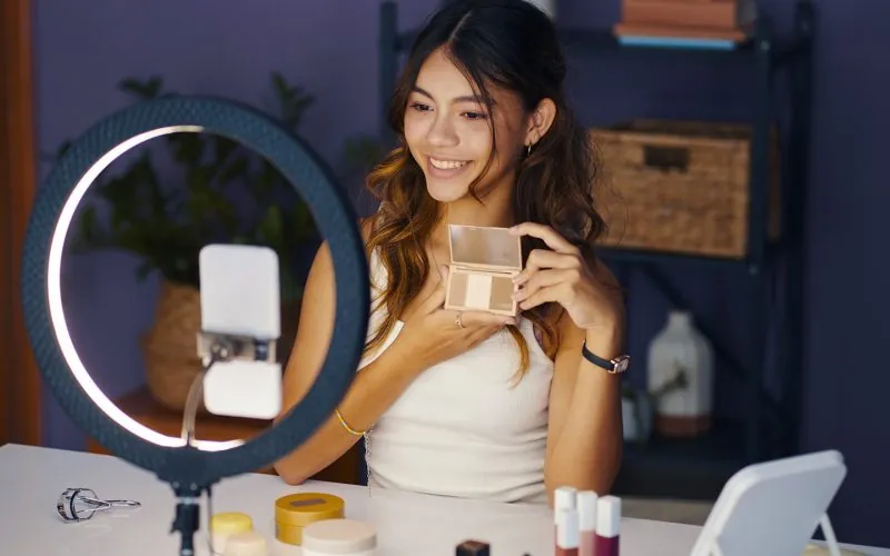 Pige sidder foran sin telefon med sin makeup