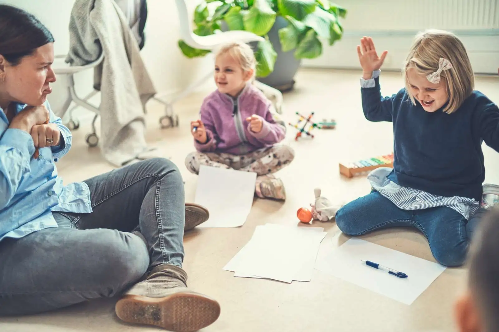 Kvinde og to børn sidder på gulvet og lader som om de er sure