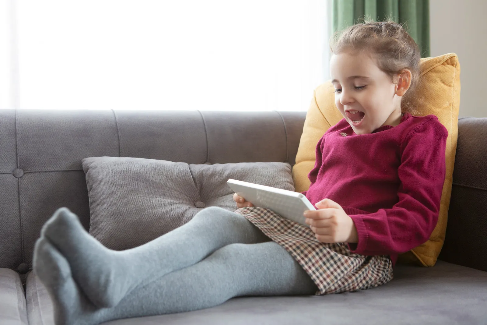 Brunhåret pige på en sofa kigger på en iPad.