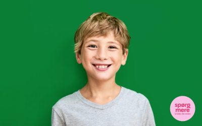 Lyshåret dreng på grøn baggrund smiler til kameraet.