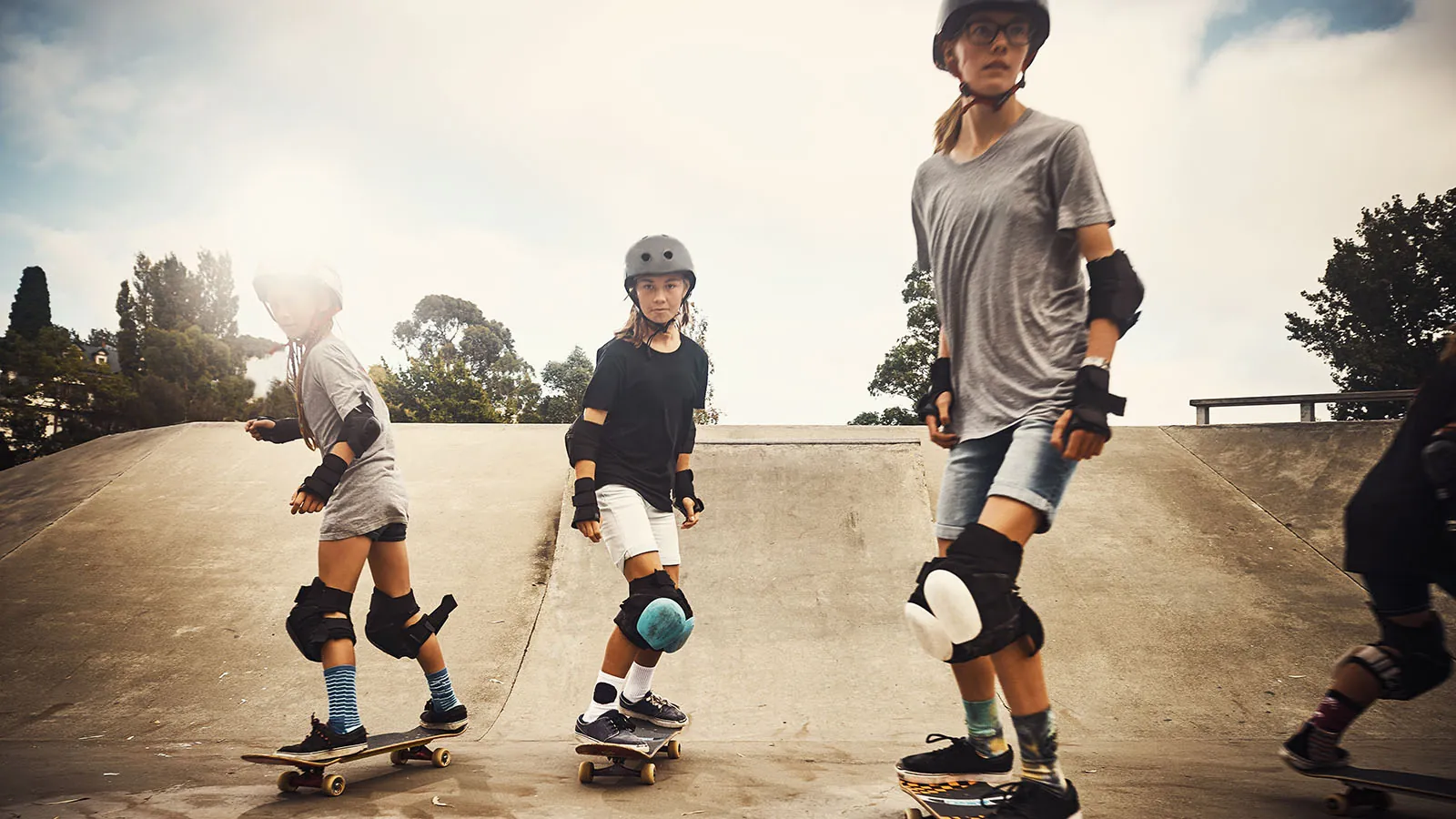 Tre piger, der står på skateboard sammen