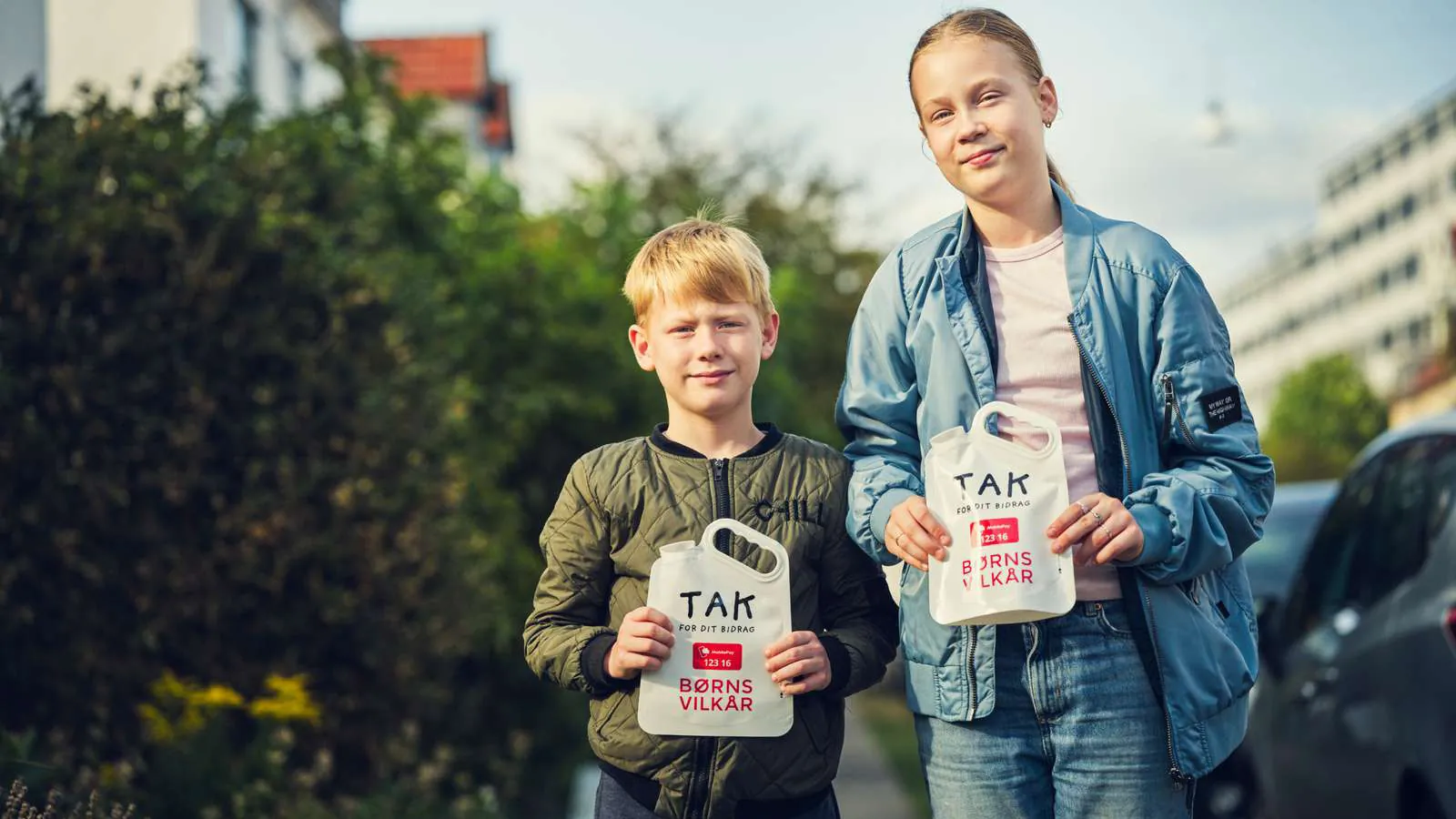 En dreng og en pige står med deres indsamlingsposer fra landsindsamlingen