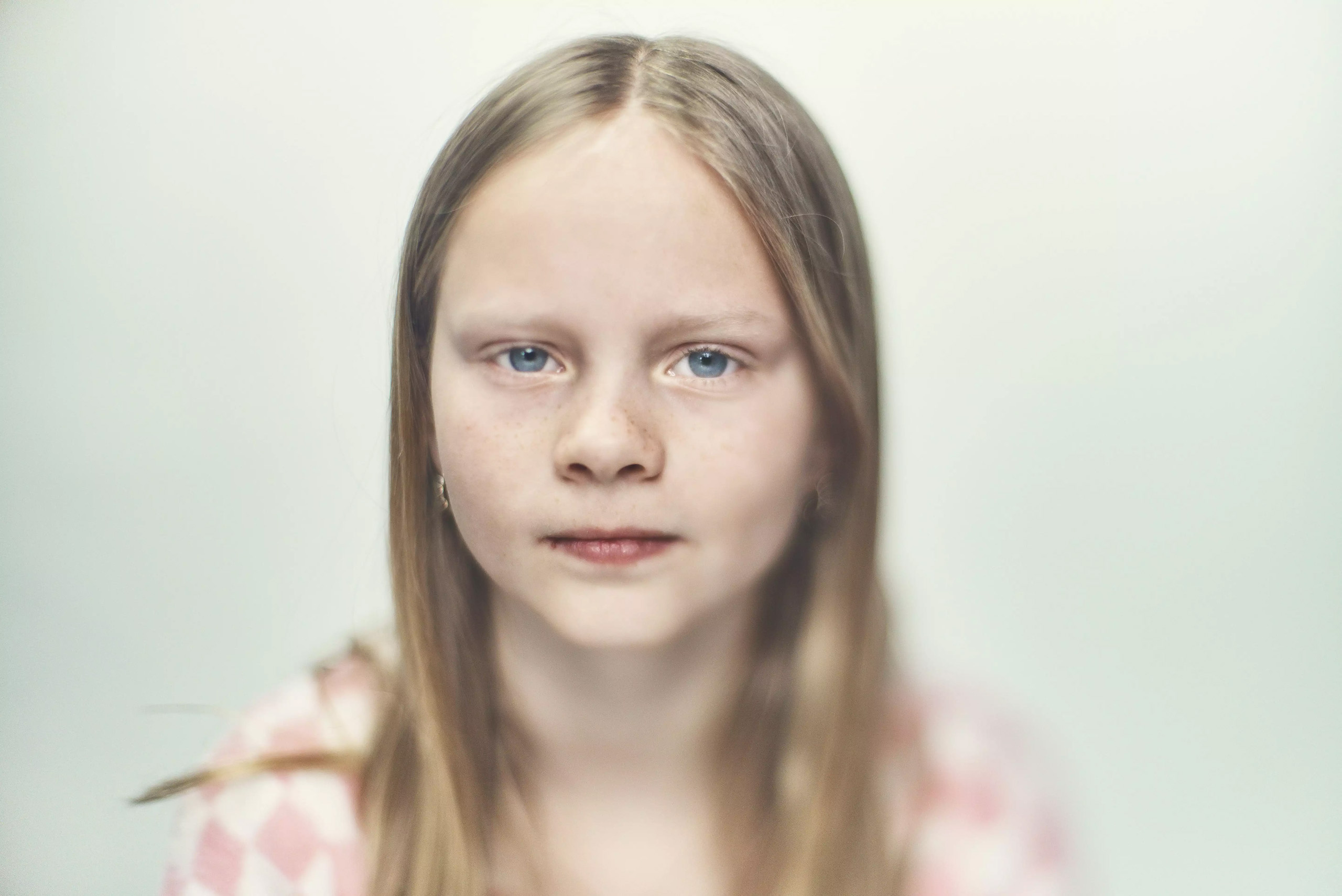 Pige på hvid baggrund kigger ind i kameraet